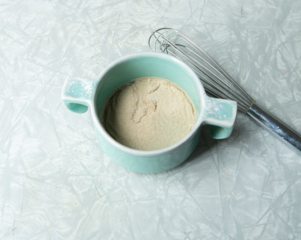 yeast sprinkled in a bowl with whisk