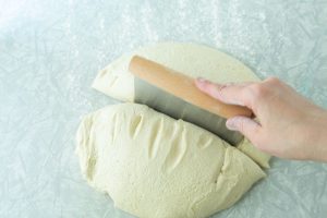dividing bread dough in half with bench scraper