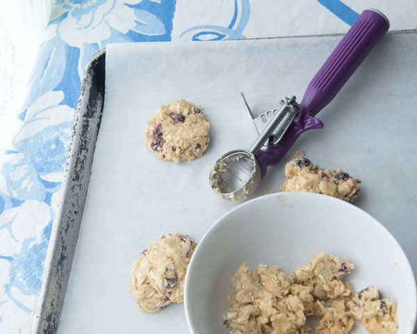 baking scoop, oatmeal cookie dough and bowl on baking sheet