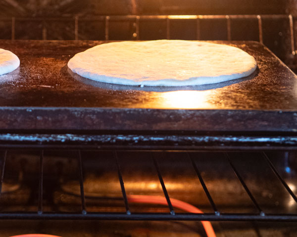 pita dough in oven on inverted baking sheet