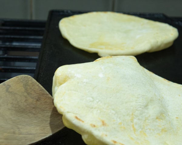 pita breads on cast iron griddle after flipping