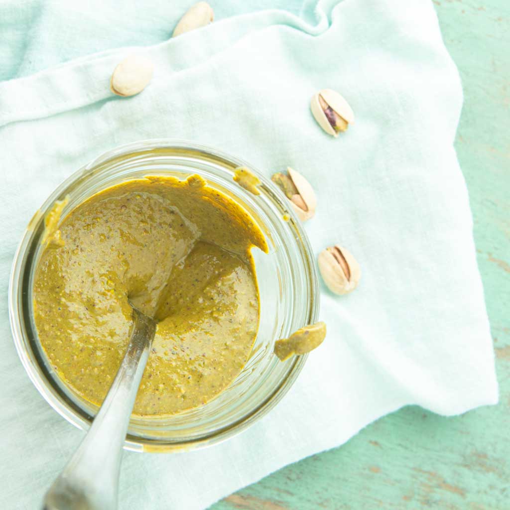 homemade pistachio butter in jar with whole pistachios