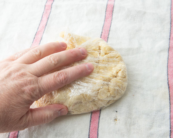 pressing dough together inside a piece of plastic wrap