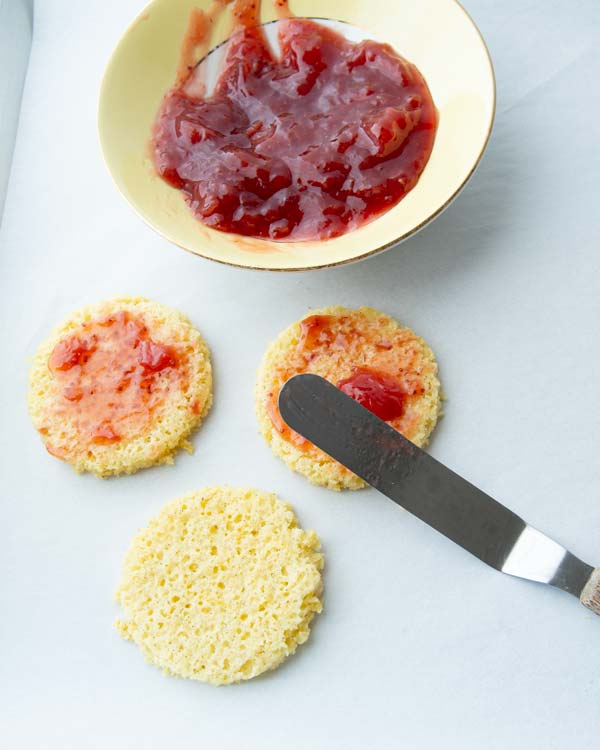 Spreading strawberry mini cakes layers with strawberry jam