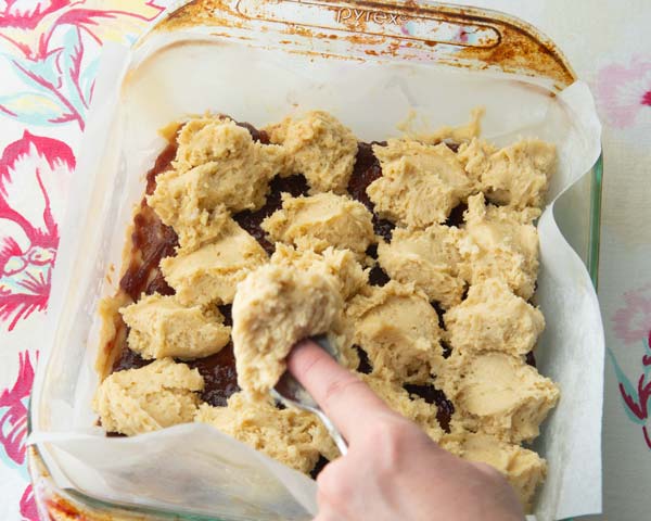 spreading dollops of cake batter over jam