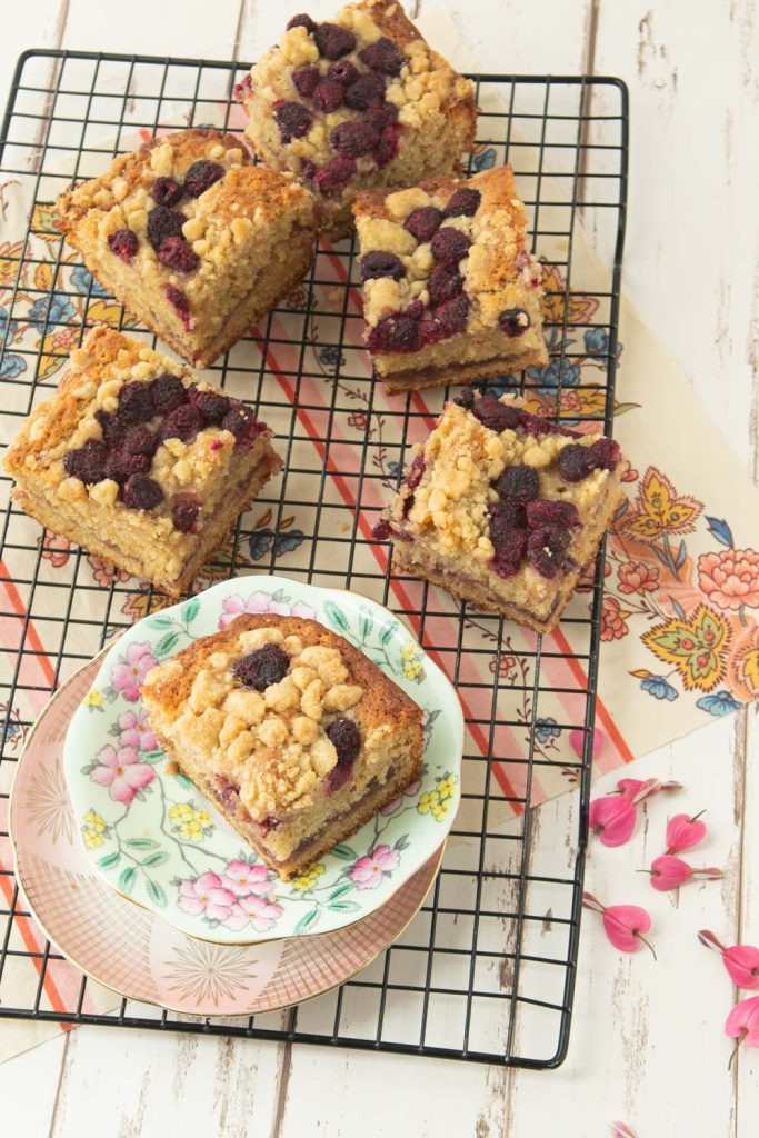 pieces of raspberry sour cream coffee cake on wire rack and plates