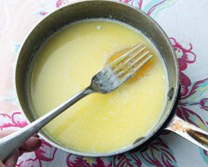 adding egg to warm butter and milk