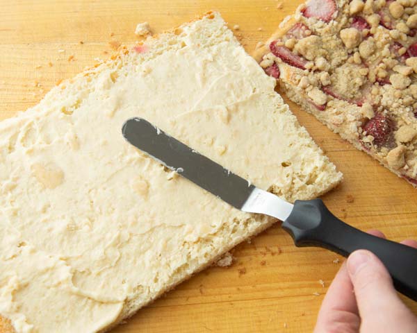 spreading marzipan filling onto strawberry sheet cake layer