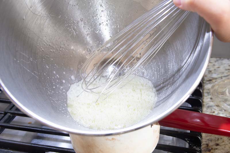 whisking egg whites over simmering water