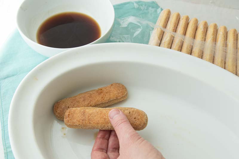 placing soaked ladyfingers in dish