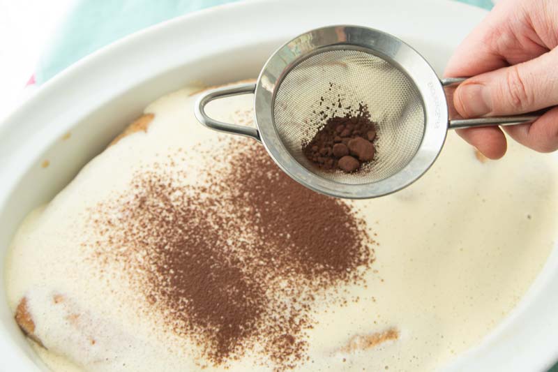 sifting cocoa over tiramisu