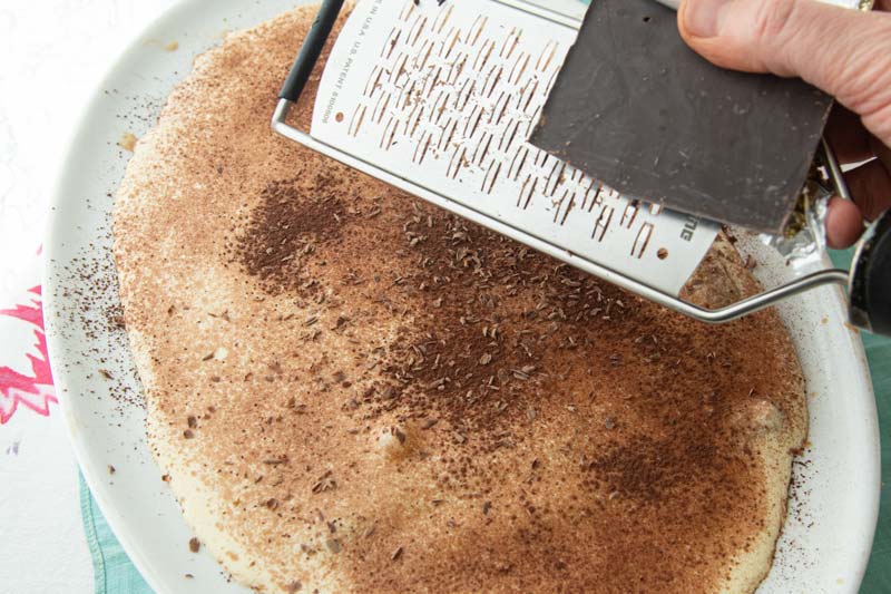 grating chocolate over tiramisu