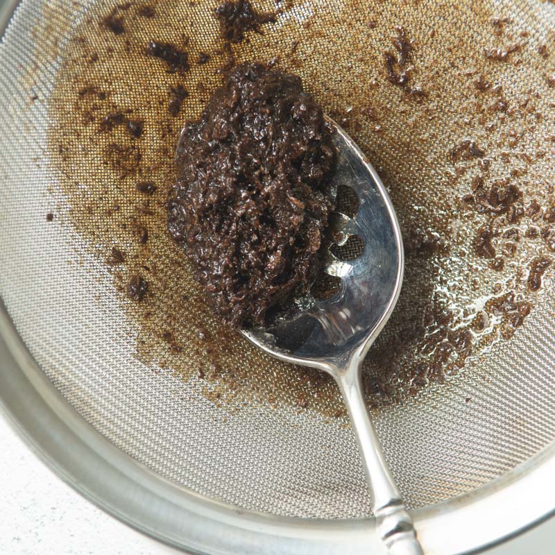 pressing vanilla bean paste through strainer