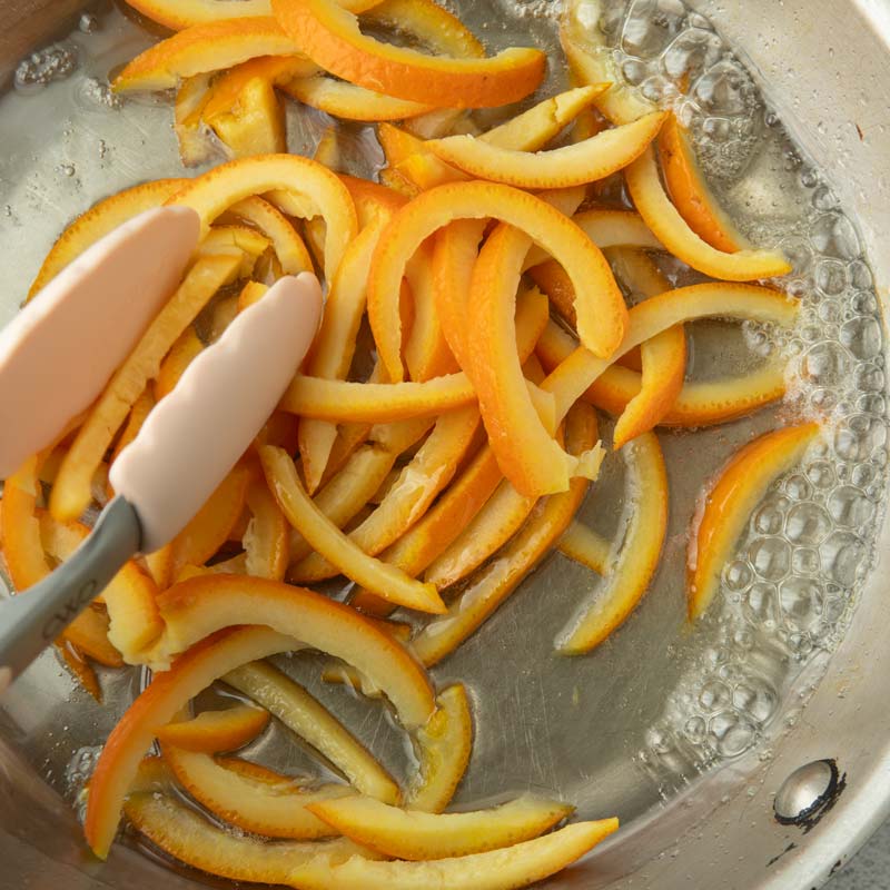 tossing orange peel strips in syrup