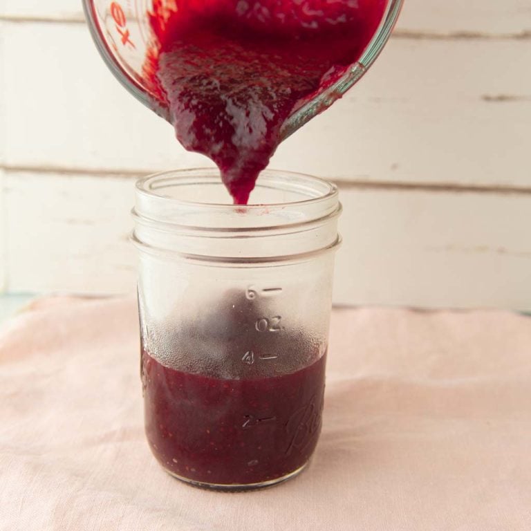 pouring homemade strawberry jam into jar