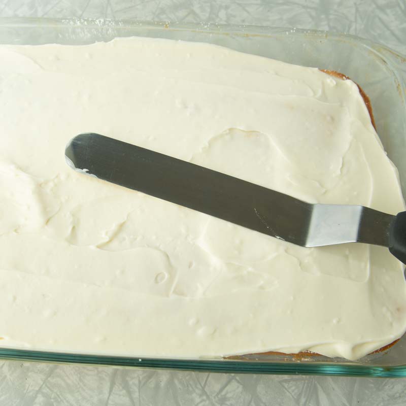 smoothing cream cheese icing over cake
