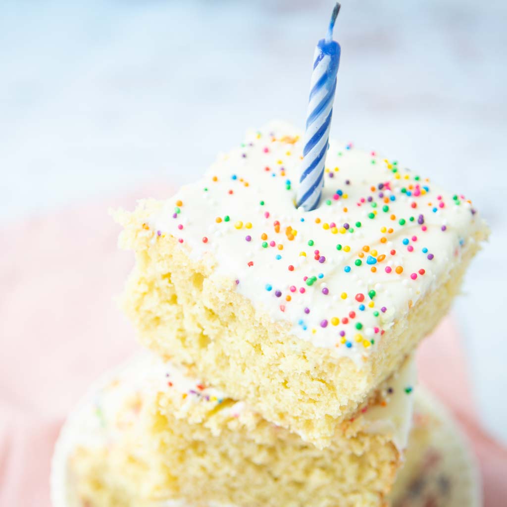 stacked pieces of vanilla sheet cake with birthday candle