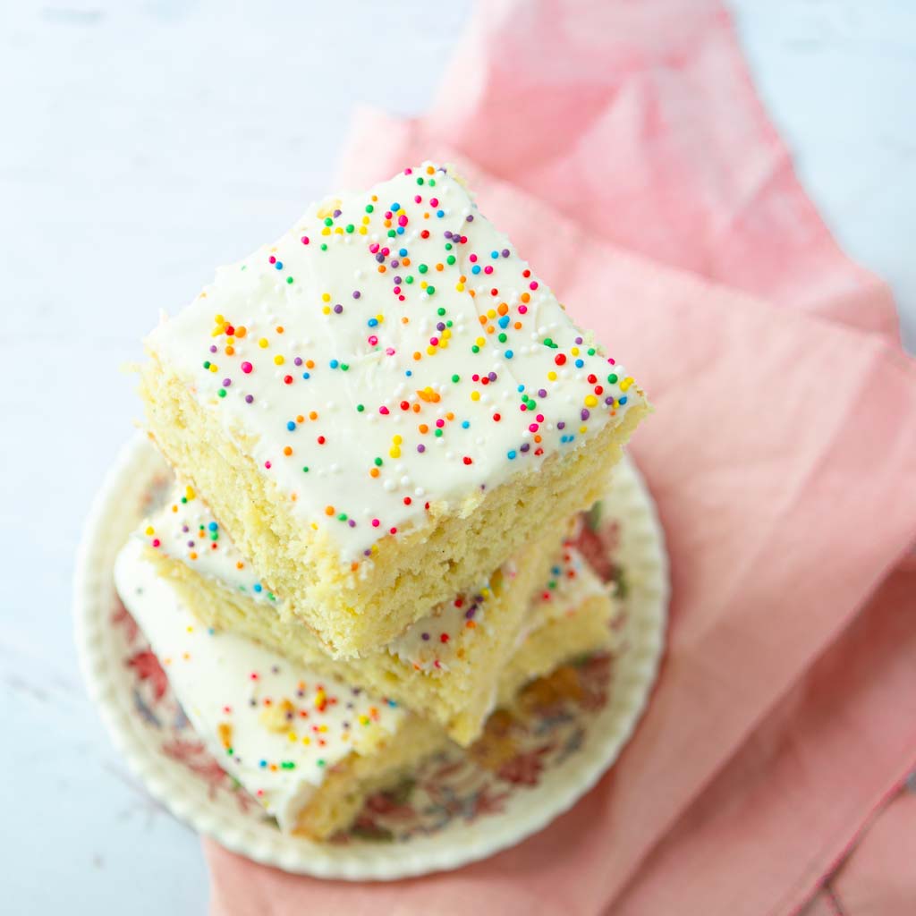 stacked pieces of vanilla sheet cake on plate on napkin