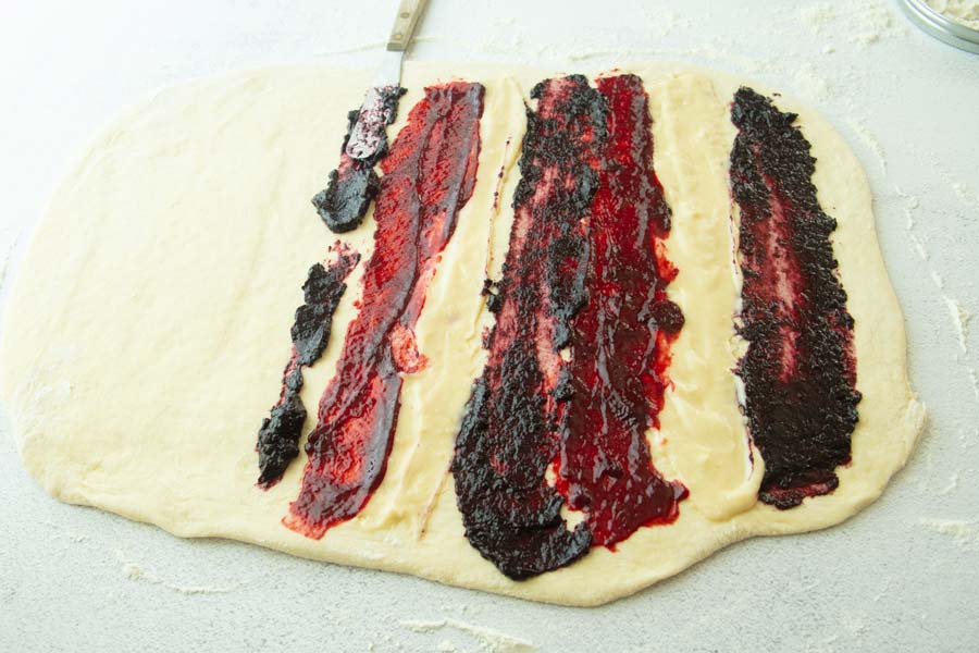 spreading stripes of jam on dough