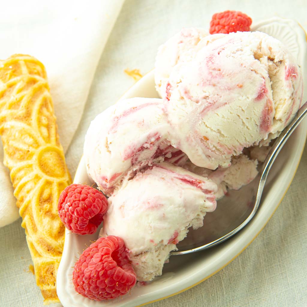raspberry swirl ice cream in bowl with raspberries and krumkake cookie