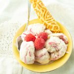 raspberry swirl ice cream in bowl with krumkake cookie and raspberries