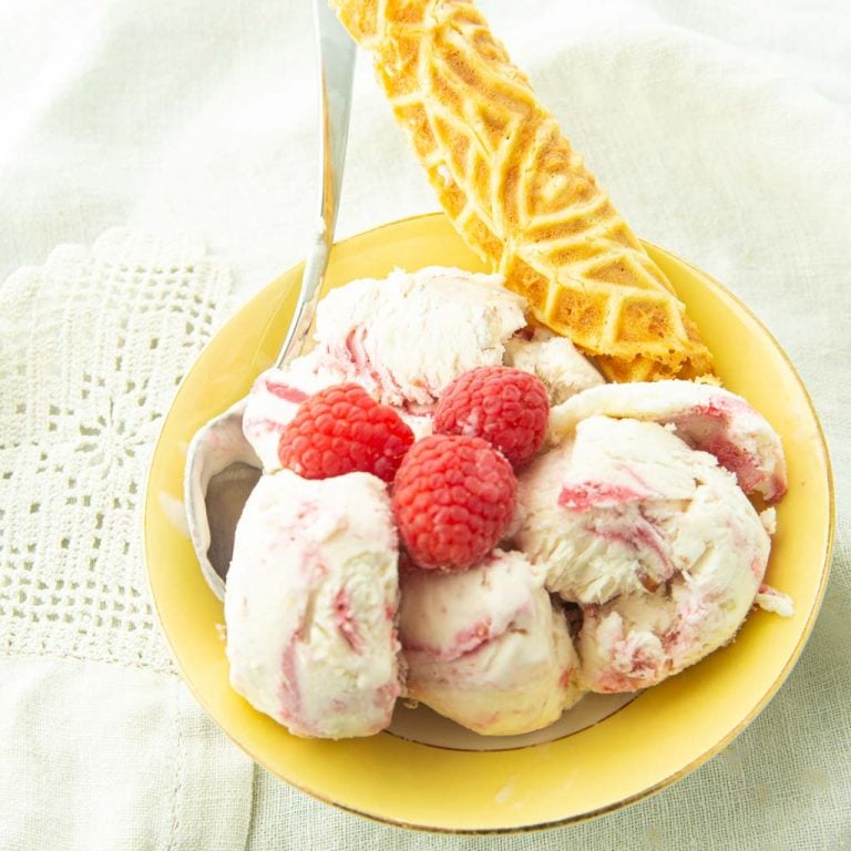 raspberry swirl ice cream in bowl with krumkake cookie and raspberries