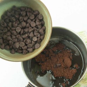 pouring chocolate chips into cocoa and butter