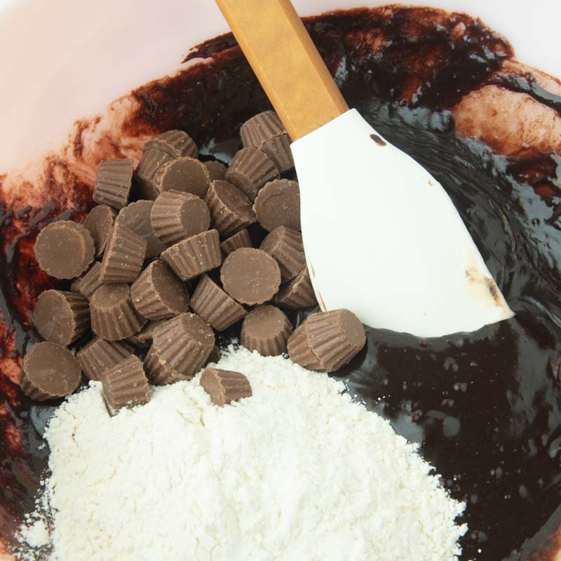 folding flour and peanut butter cups into brownie batter
