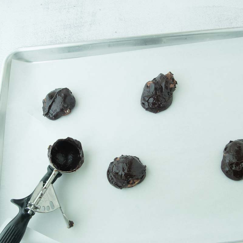 scooping brownie cookies onto sheet tray