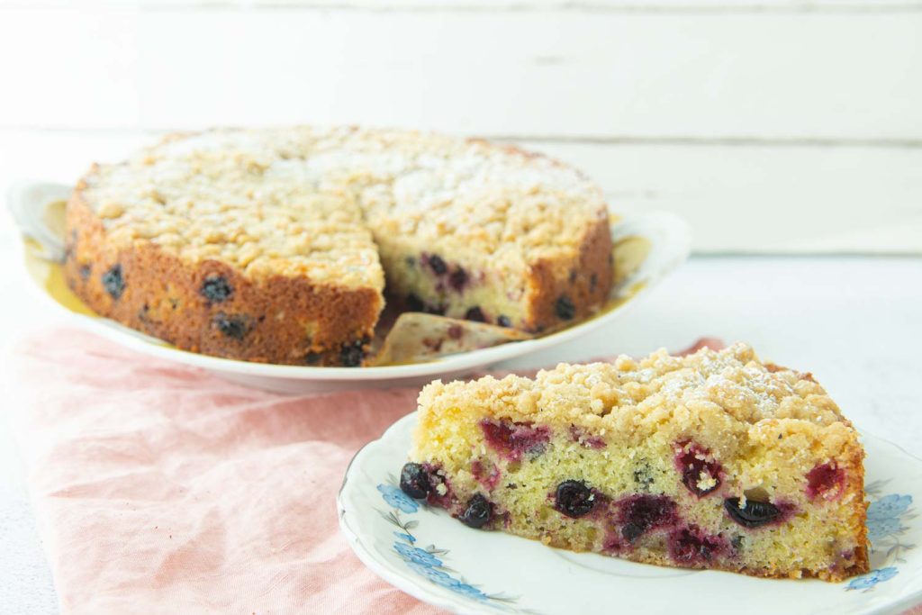 slice of black currant cake on plate with whole cake in background