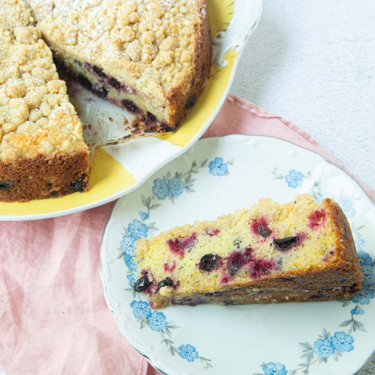 slice of black currant cake on plate with whole cake in background