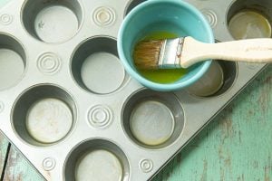 brushing muffin tin with butter