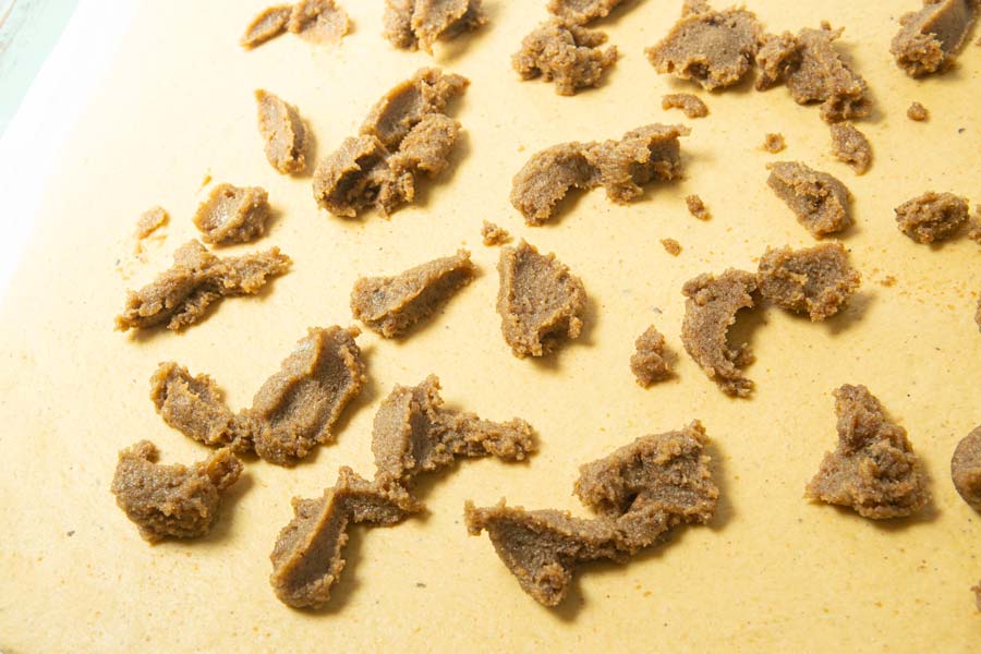spreading brown sugar paste on pumpkin cinnamon roll dough