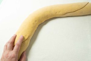 rolling up log of pumpkin roll dough for pumpkin cinnamon rolls