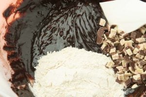 mixing flour and peppermint bark into brownie batter