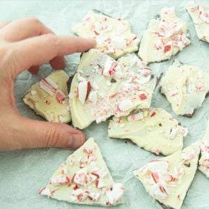 hand holding piece of peppermint bark among pieces of peppermint bark