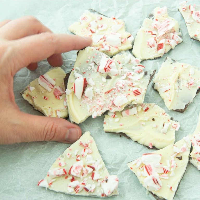 hand holding piece of peppermint bark among pieces of peppermint bark