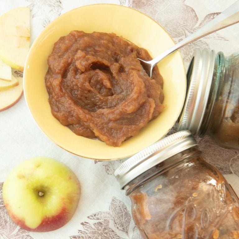 homemade apple butter recipe in bowl with spoon, apple and jars of apple butter