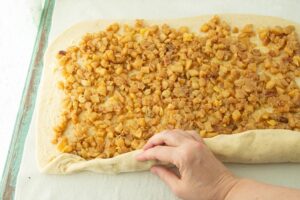 rolling dough over apple filling for apple pie cinnamon rolls