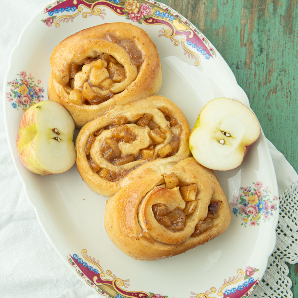 apple pie cinnamon rolls on plate with cut apples