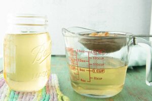 straining lard into glass measuring cup with jar of Mason jar of lard