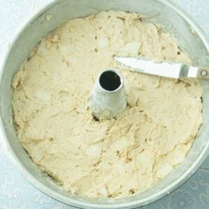 smoothing apple cake batter into tube pan