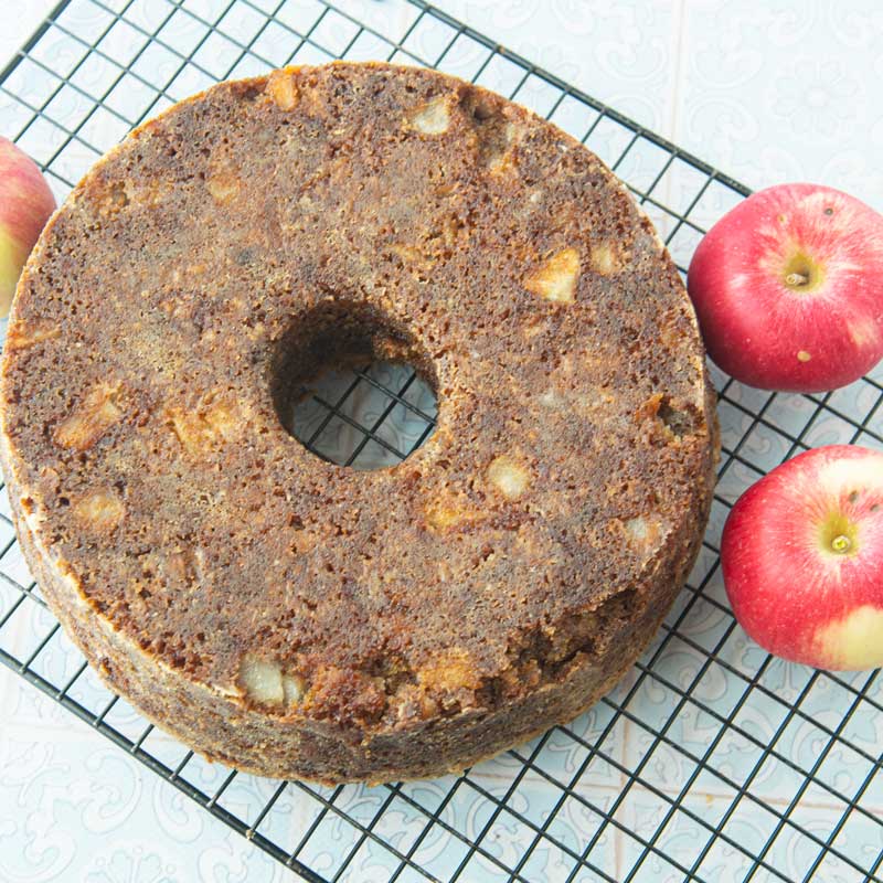 apple cake cooling on cake rack with apples