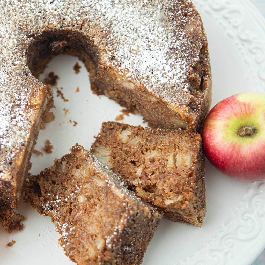closeup of apple cake slices, apple cake, and whole apple