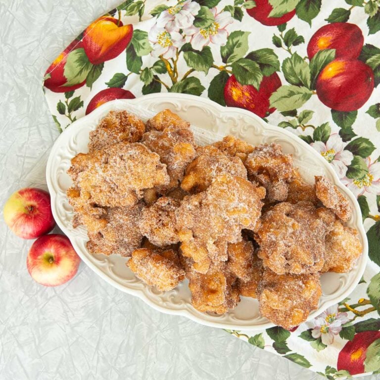 platter of apple fritters with whole apples on apple tablecloth