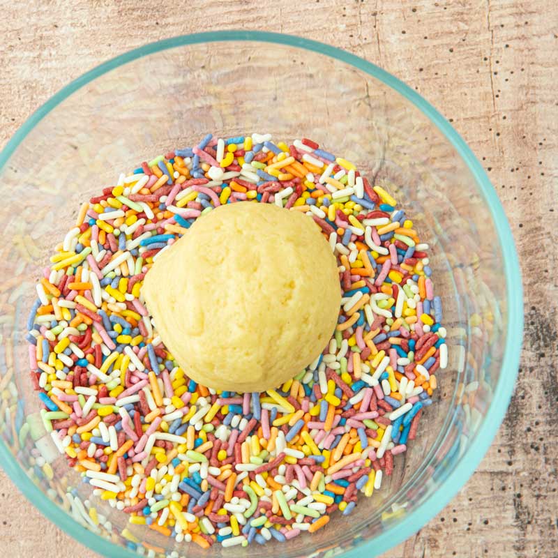 rolling sugar cookie dough in sprinkles