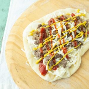 assembling cheeseburger pizza on pizza peel