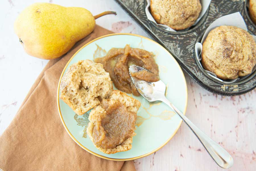 pear butter on muffin with spoon and whole pears