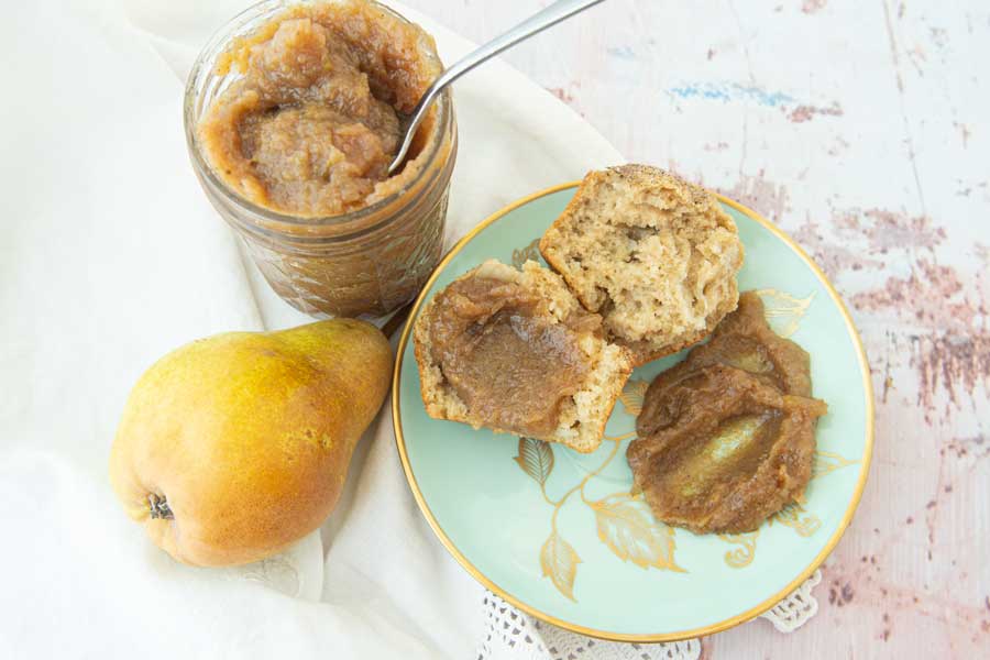 pear butter on muffin with spoon and whole pears
