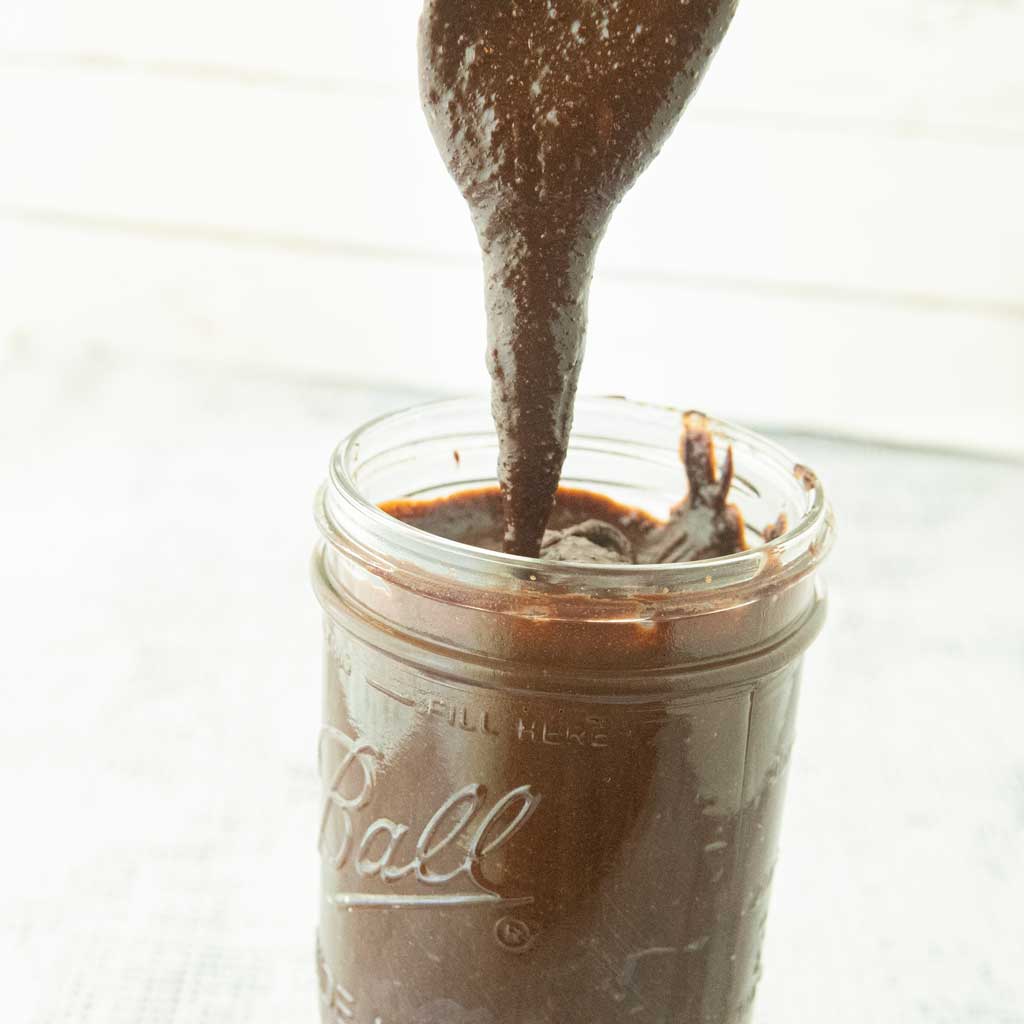 dripping homemade nutella into jar from spoon